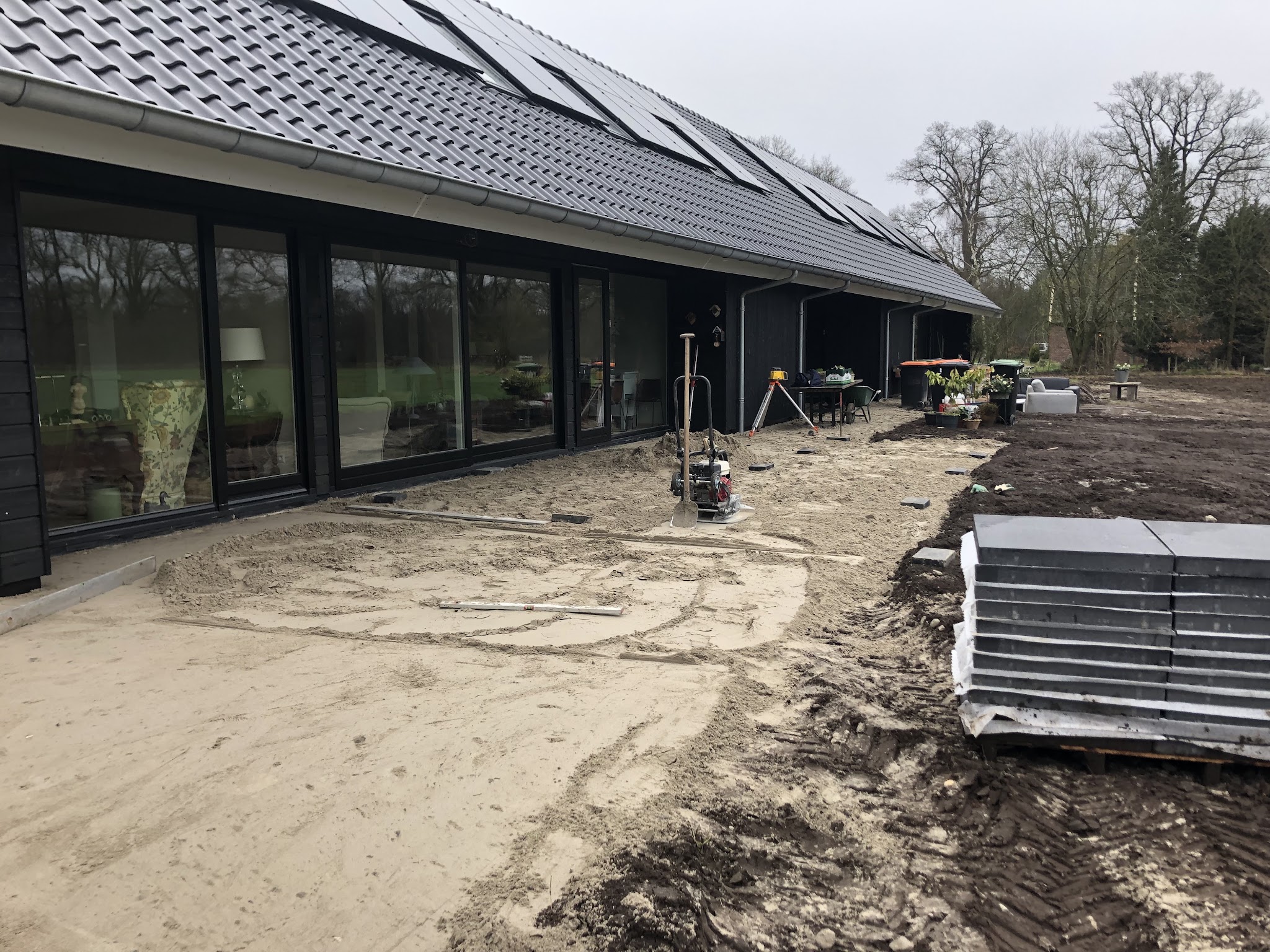 Lange moderne bungalow met een zandbed en een stapel tegels klaar om te leggen